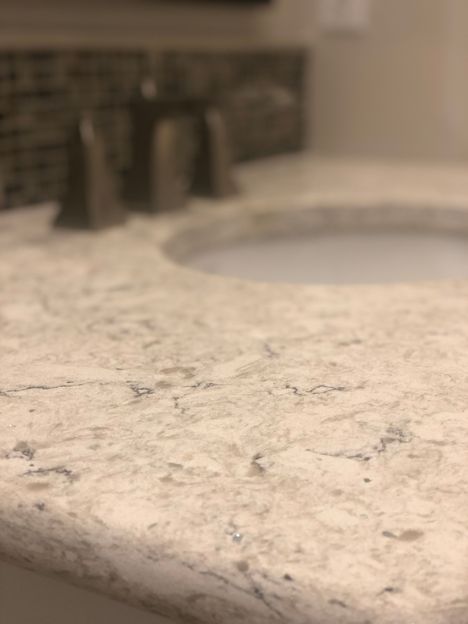 A modern white marble kitchen island with a sleek faucet and sink, featuring potted plants and a minimalist aesthetic.