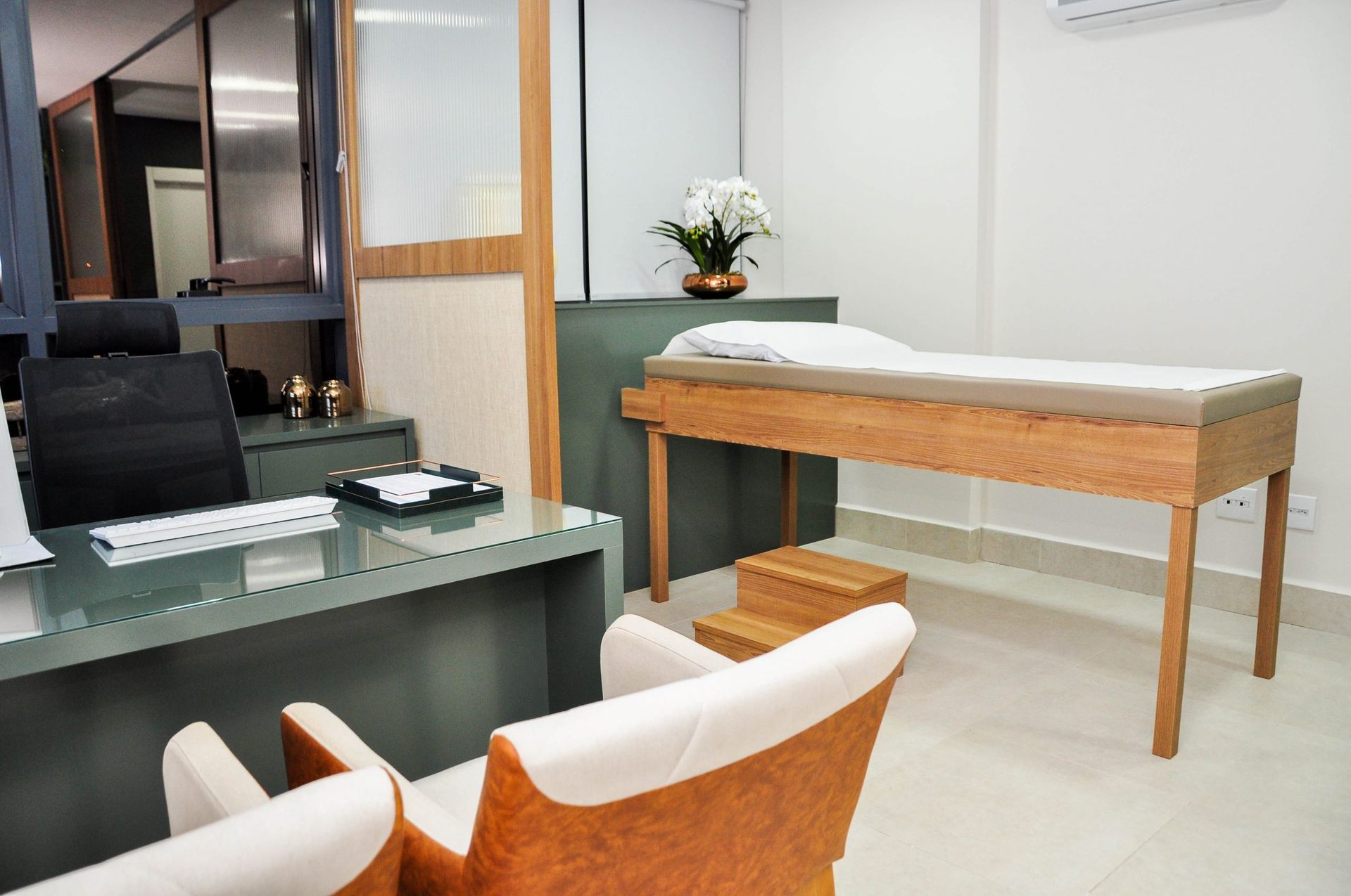 Um consultório médico com uma mesa, cadeiras e uma cama.