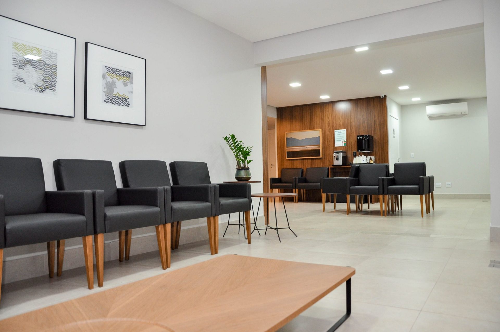 Uma sala de espera com uma fileira de cadeiras e uma mesa.