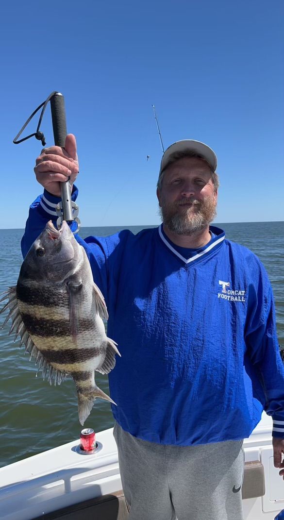 A man in a blue shirt is holding a fish on a boat.