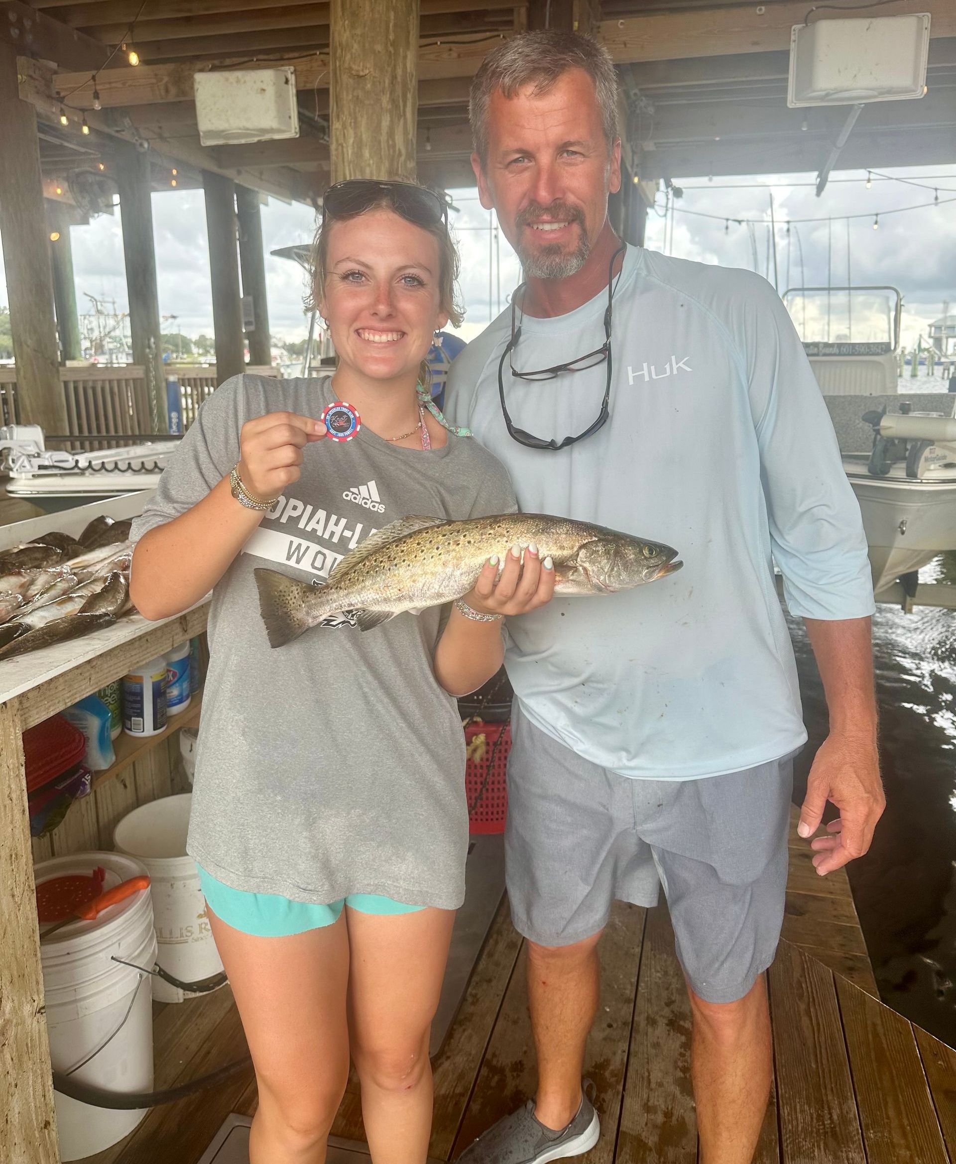 A man and a woman are standing next to each other holding a fish.