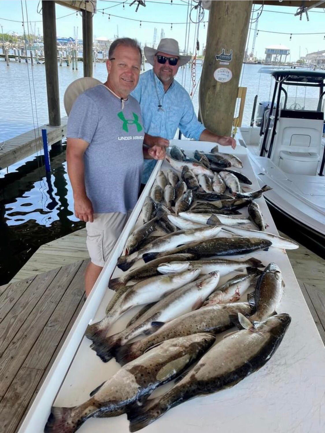 Two men are standing next to a table full of fish.