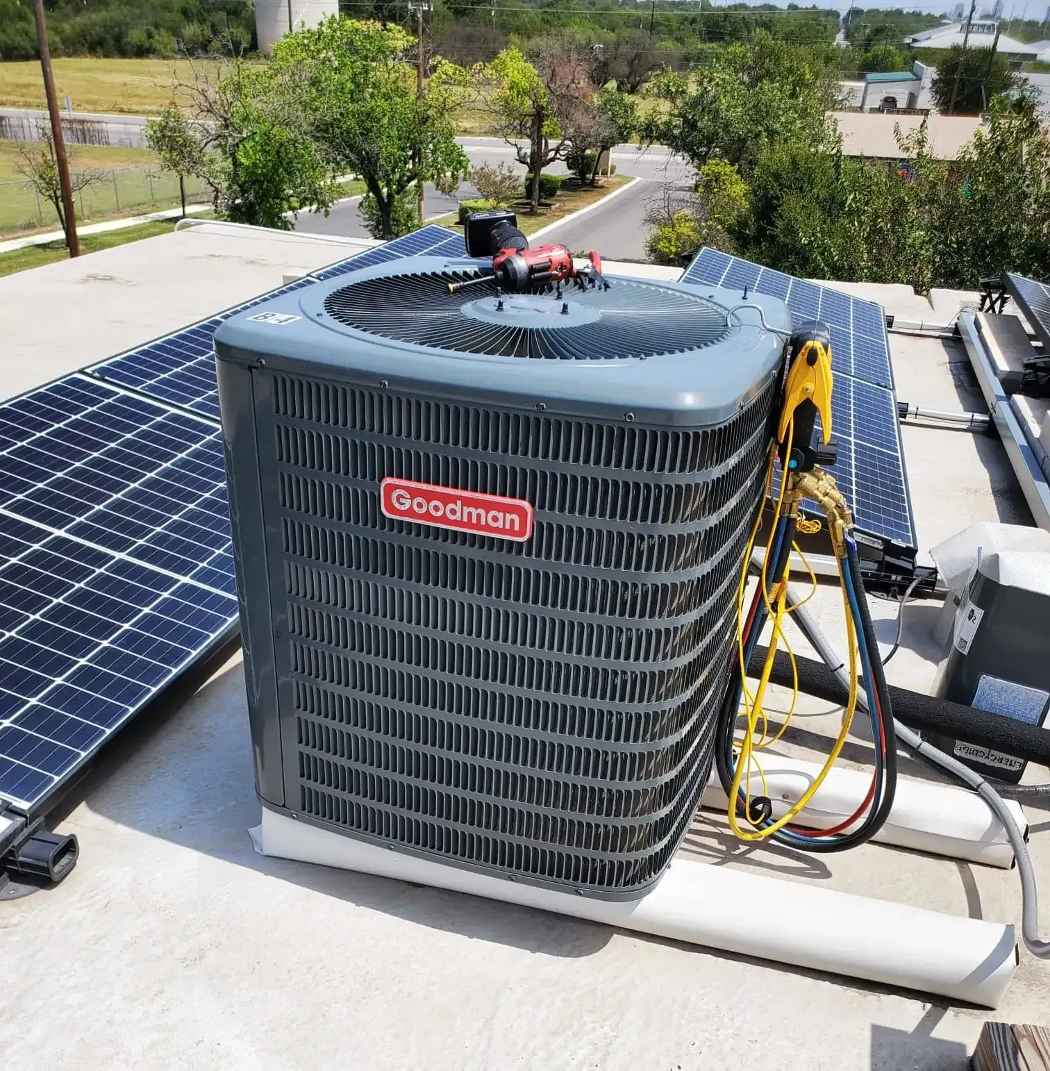 A grey HVAC outdoor unit sits on a concrete pad next to a house with blue siding and a green lawn.
