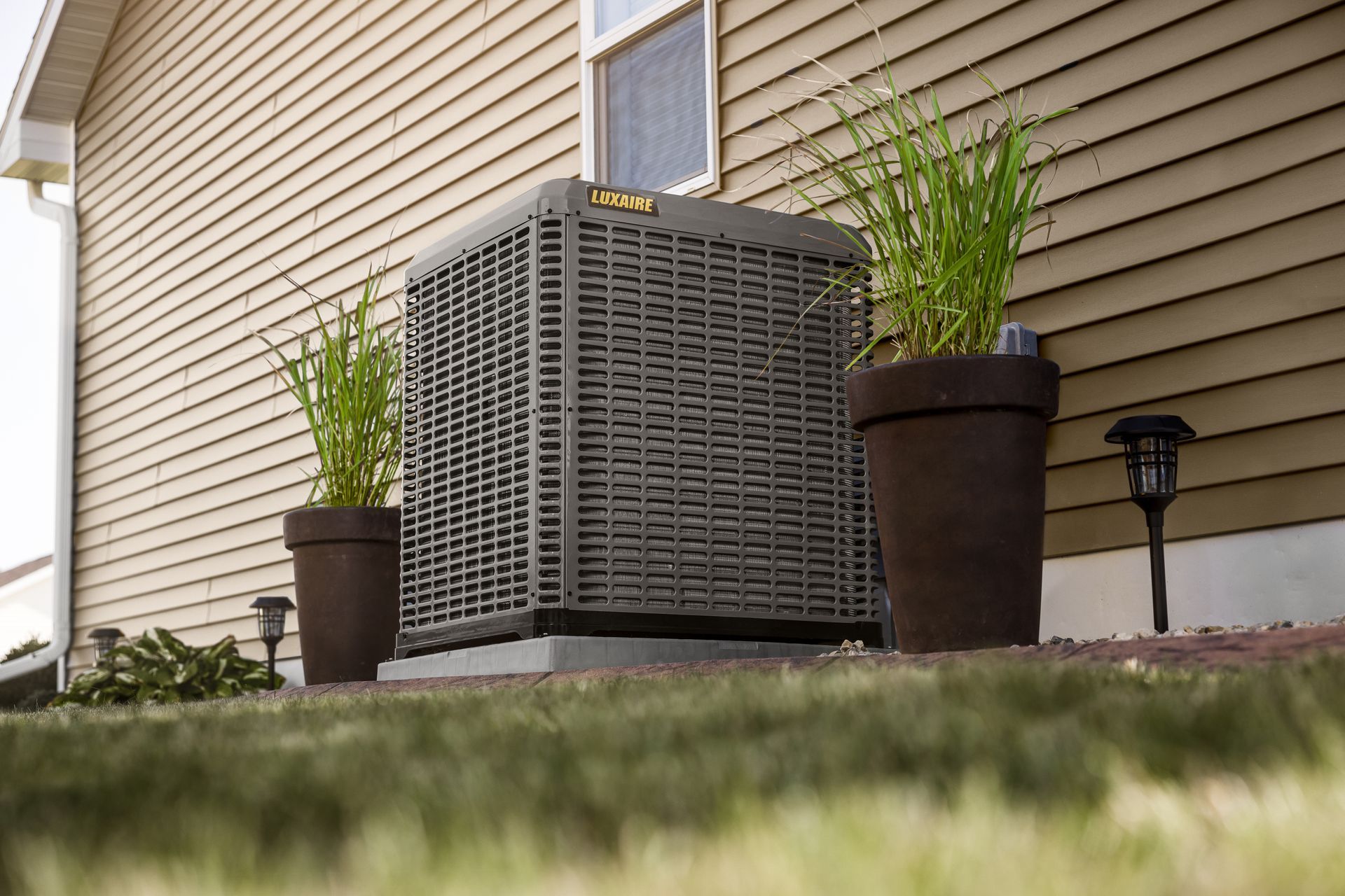 Black industrial ceiling showing exposed rectangular air ducts, pipes, and a mounted smoke detector.