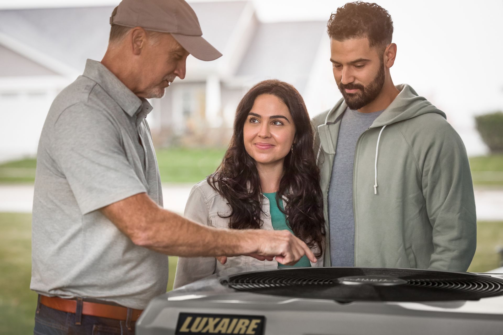 A dark gray residential furnace unit stands on a floor next to metal ductwork, featuring a red gas valve and red wiring.