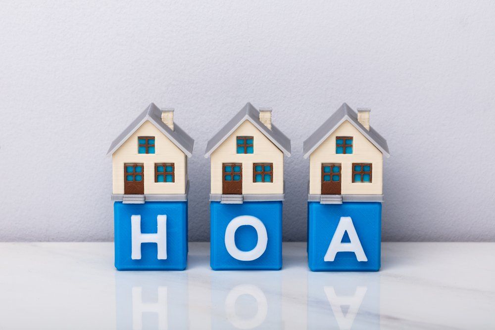 three toy houses on top of block letters that say HOA