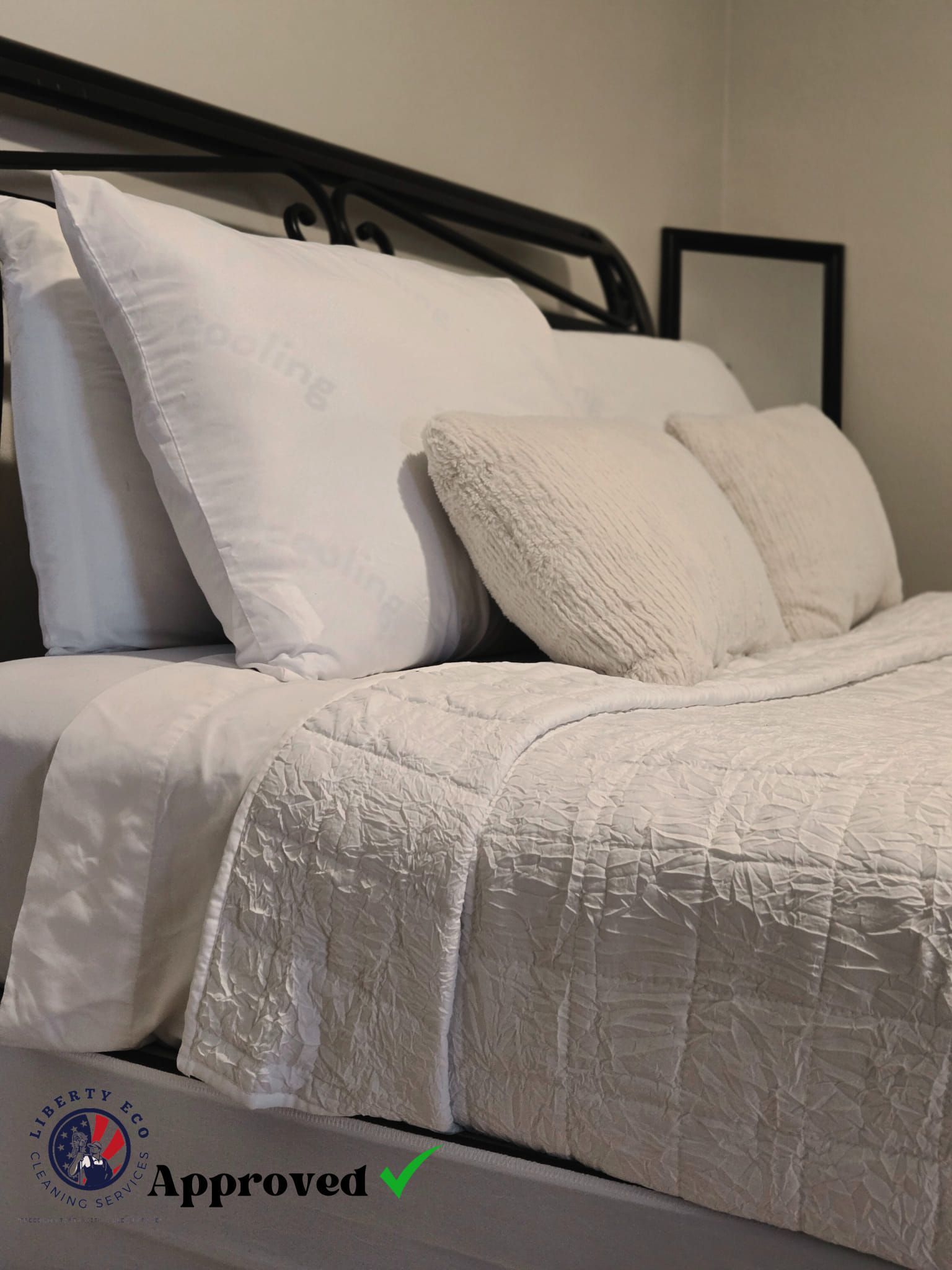 Bed with white bedding and pillows, a black headboard, and a small framed mirror.