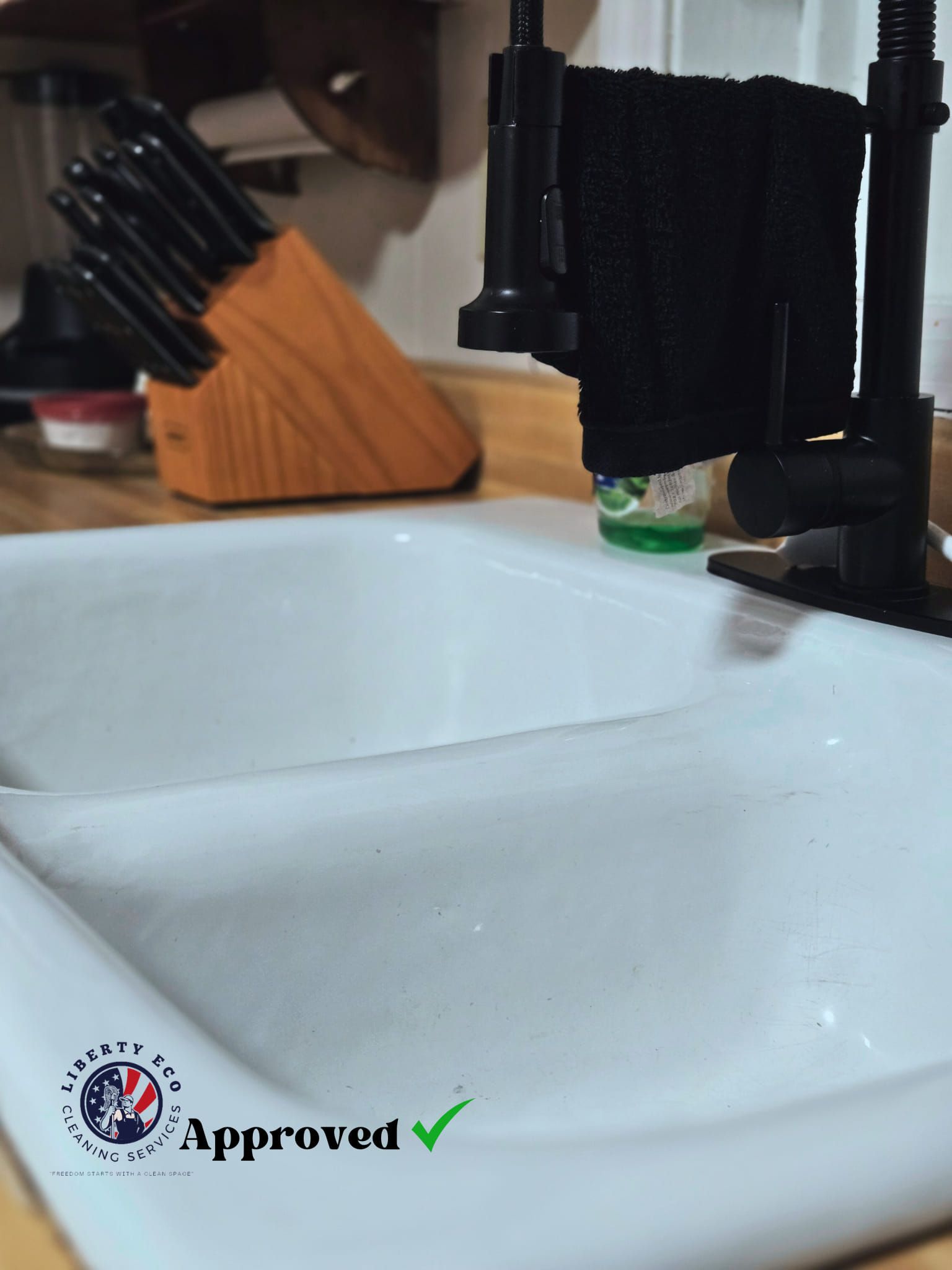 White kitchen sink with black faucet, sponge, and a knife block.