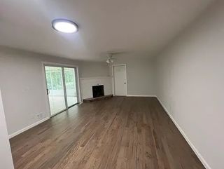 An empty living room with hardwood floors and a fireplace.