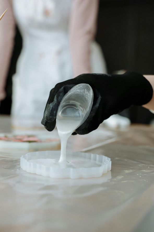 A person is pouring liquid from a cup into a bowl.