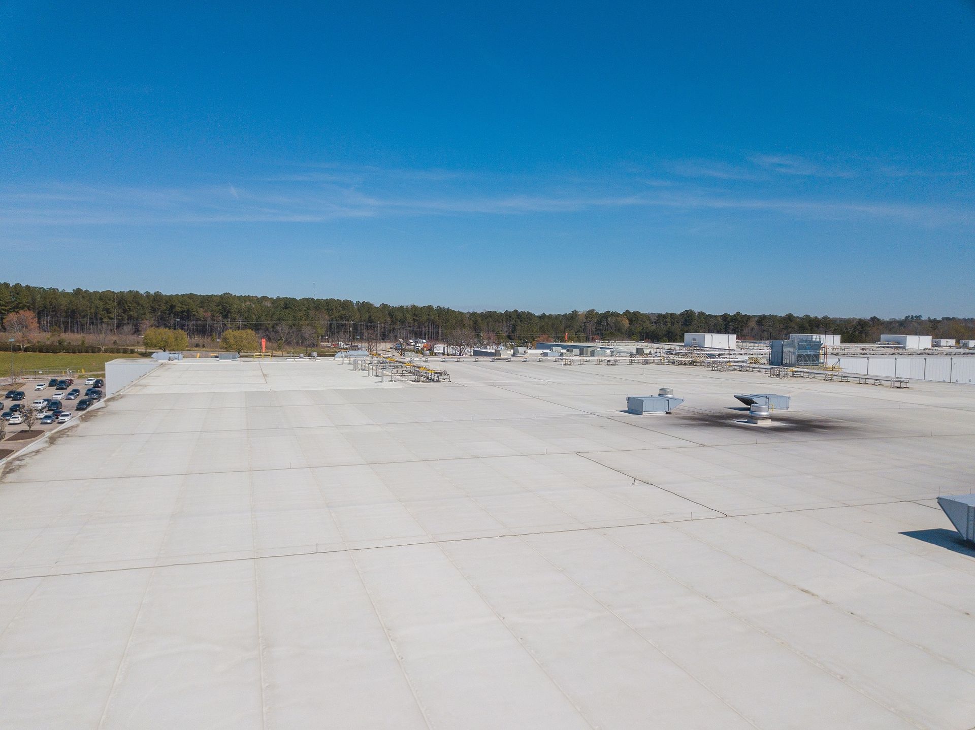 An aerial view of a large white roof with a blue sky in the background.
