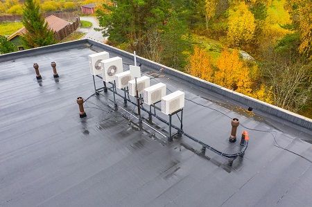 A row of air conditioners are sitting on top of a roof.