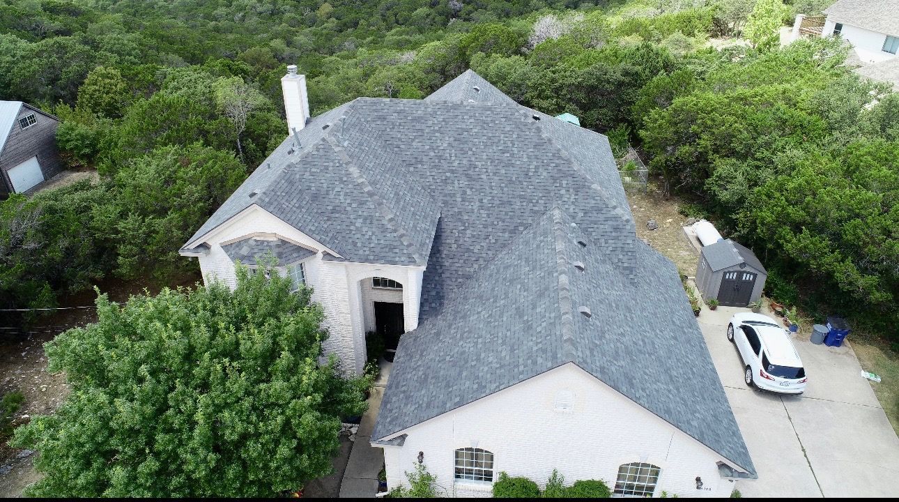 A man is standing on a ladder working on the roof of a house.
