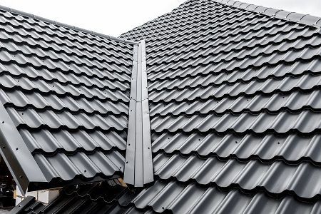 A close up of a black tiled roof with a chimney on it.