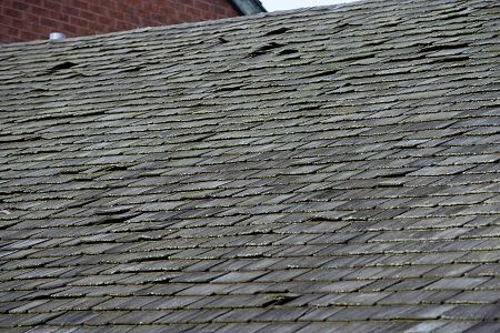 A close up of a wooden roof with a brick building in the background.