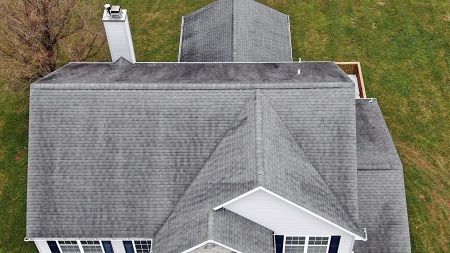 An aerial view of a house with a gray roof and a chimney.