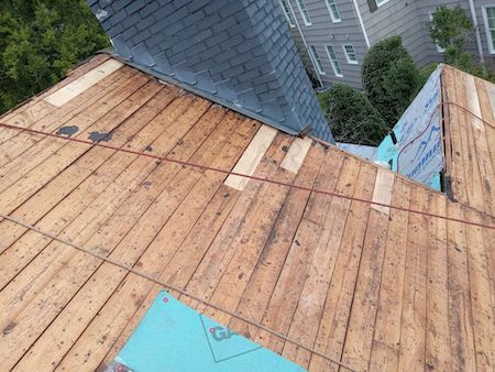 A wooden roof is being repaired with a slate chimney.
