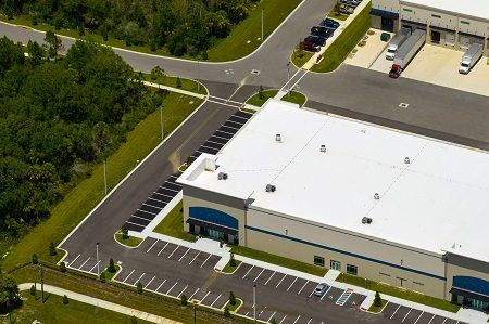 An aerial view of a large building with a white roof