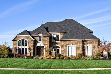A large brick house with a lush green lawn in front of it