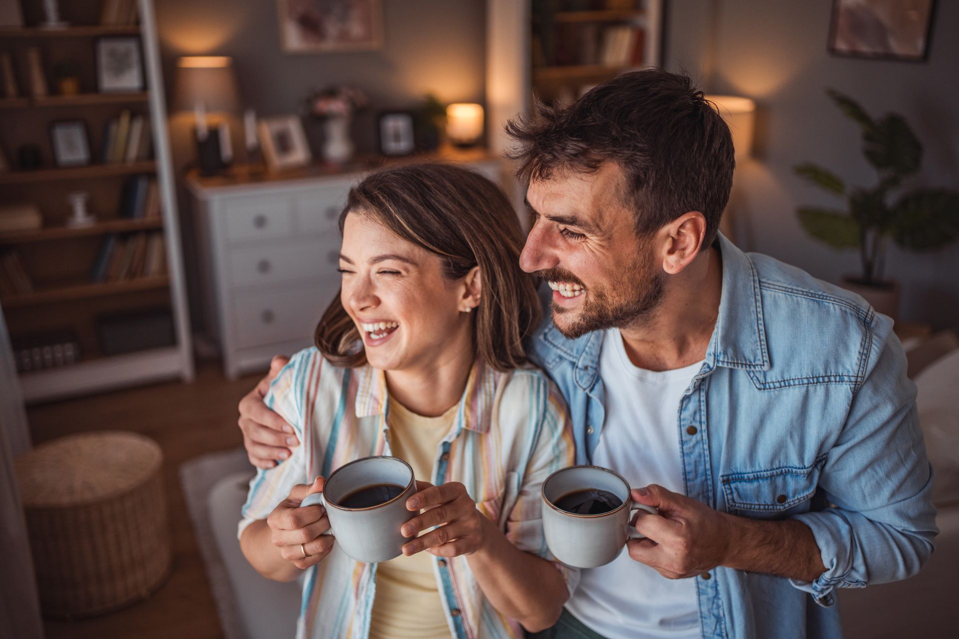 A man and a woman are sitting on a couch holding cups of coffee - Mountain Home, AR - Long Chiropractic