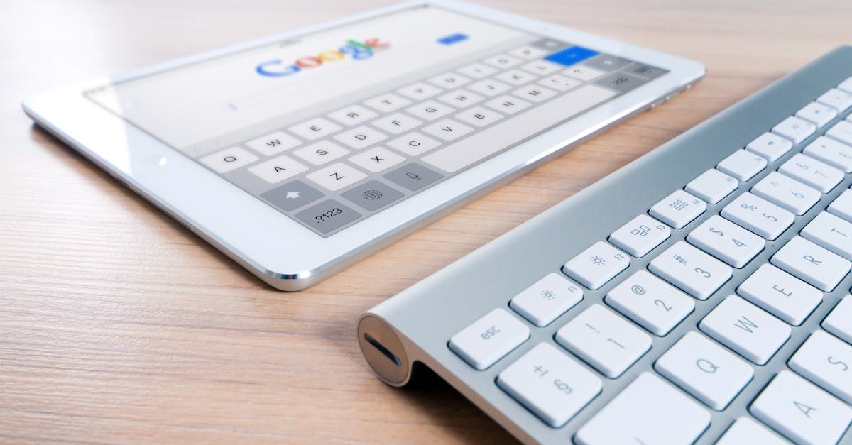 A tablet and a keyboard are on a wooden table.