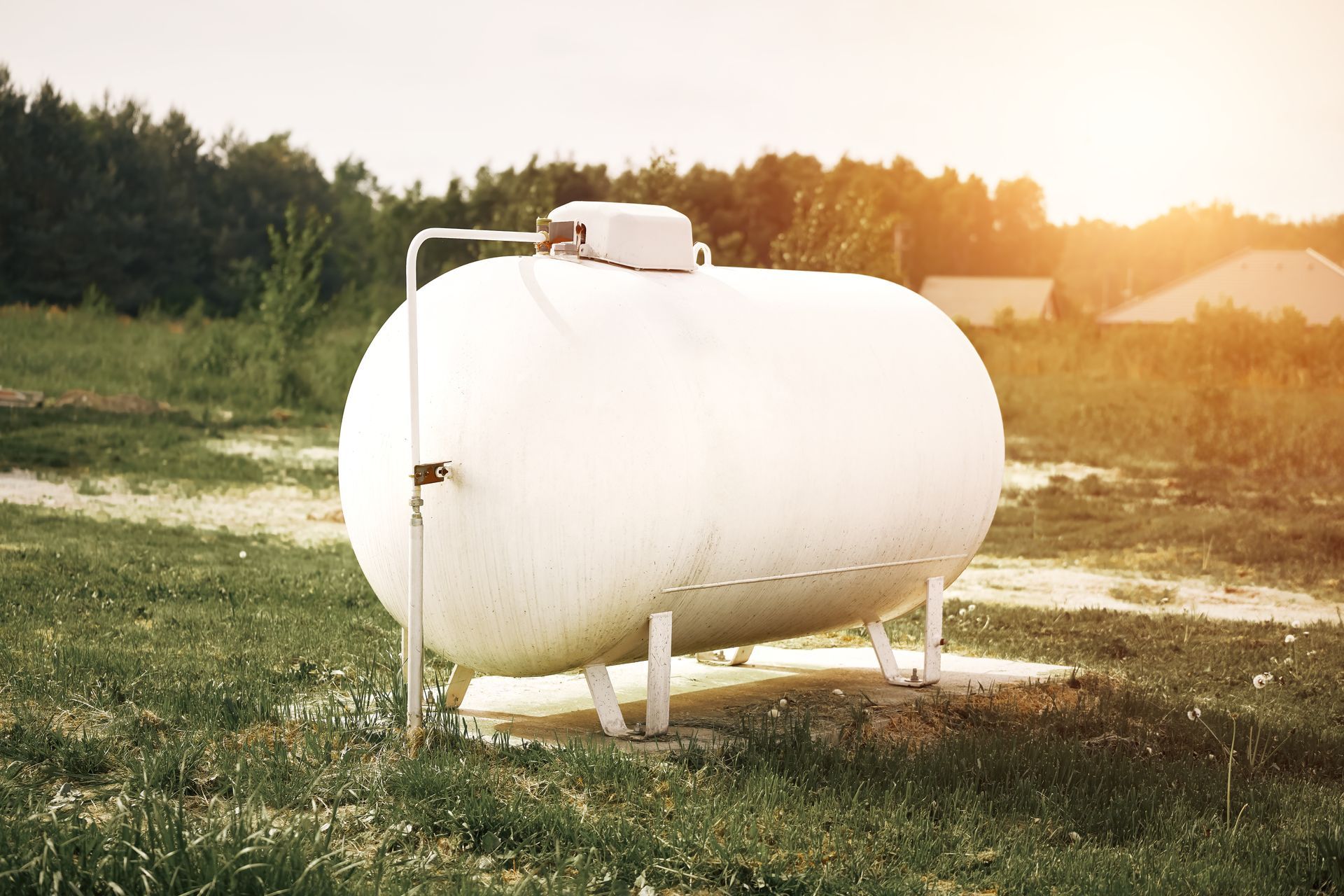 White propane tank installed on a concrete pad in a grassy yard. White propane tank installed on a concrete pad in a grassy yard.