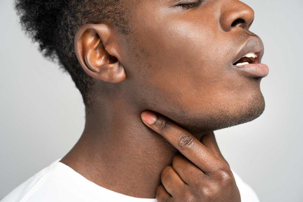 A close up of a man holding his neck with his hand.