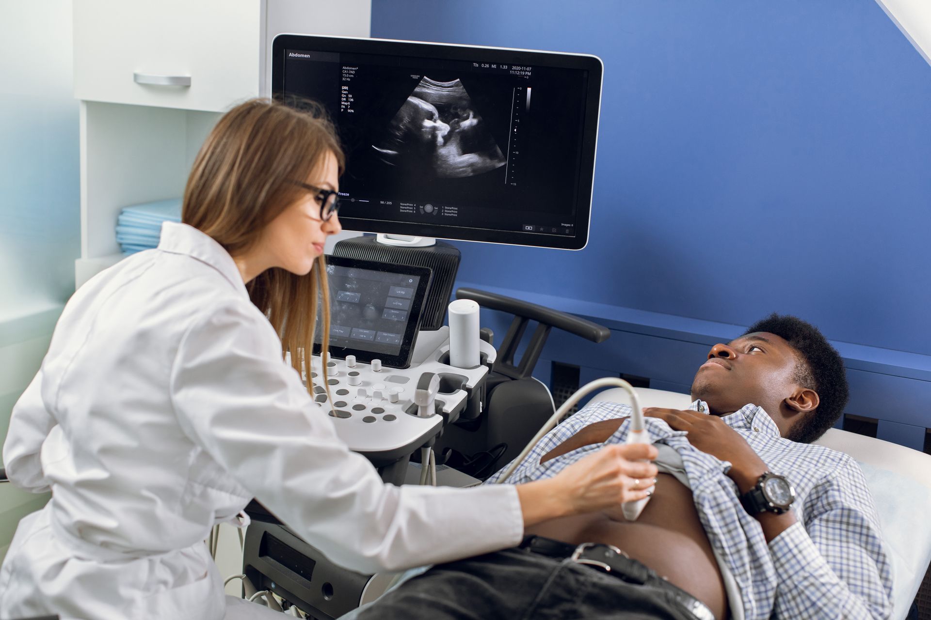 A woman is giving a man an ultrasound in a hospital.