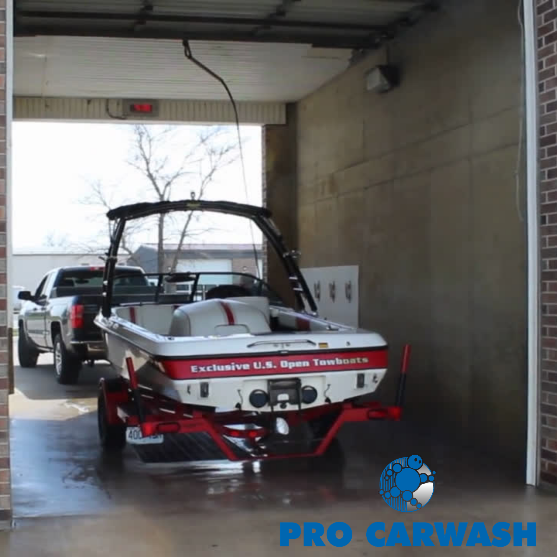 Boat trailer being washed in a car wash bay, with a black SUV behind it.