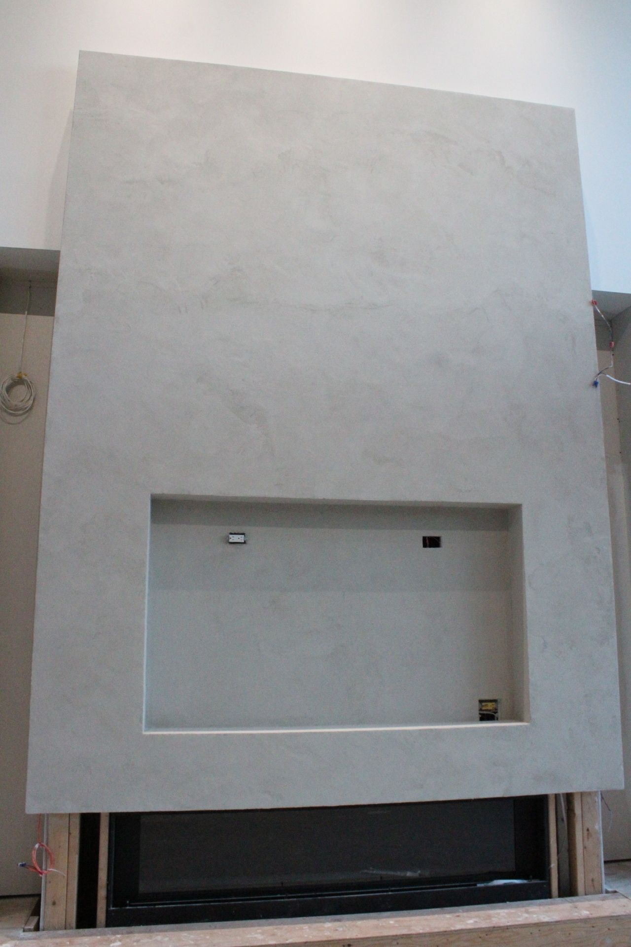 Une cheminée moderne avec une alcôve encastrée et une finition en plâtre gris.