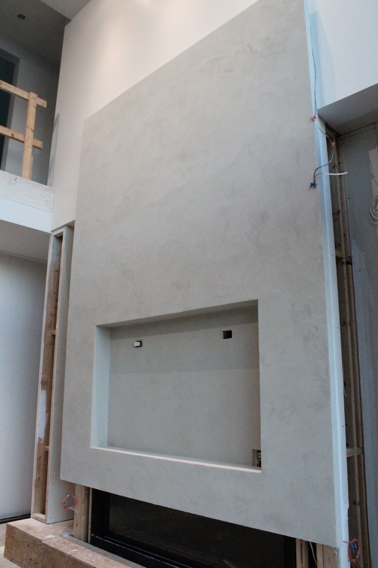 Grande cheminée de couleur claire avec ouverture rectangulaire encastrée pour une télévision, en construction.