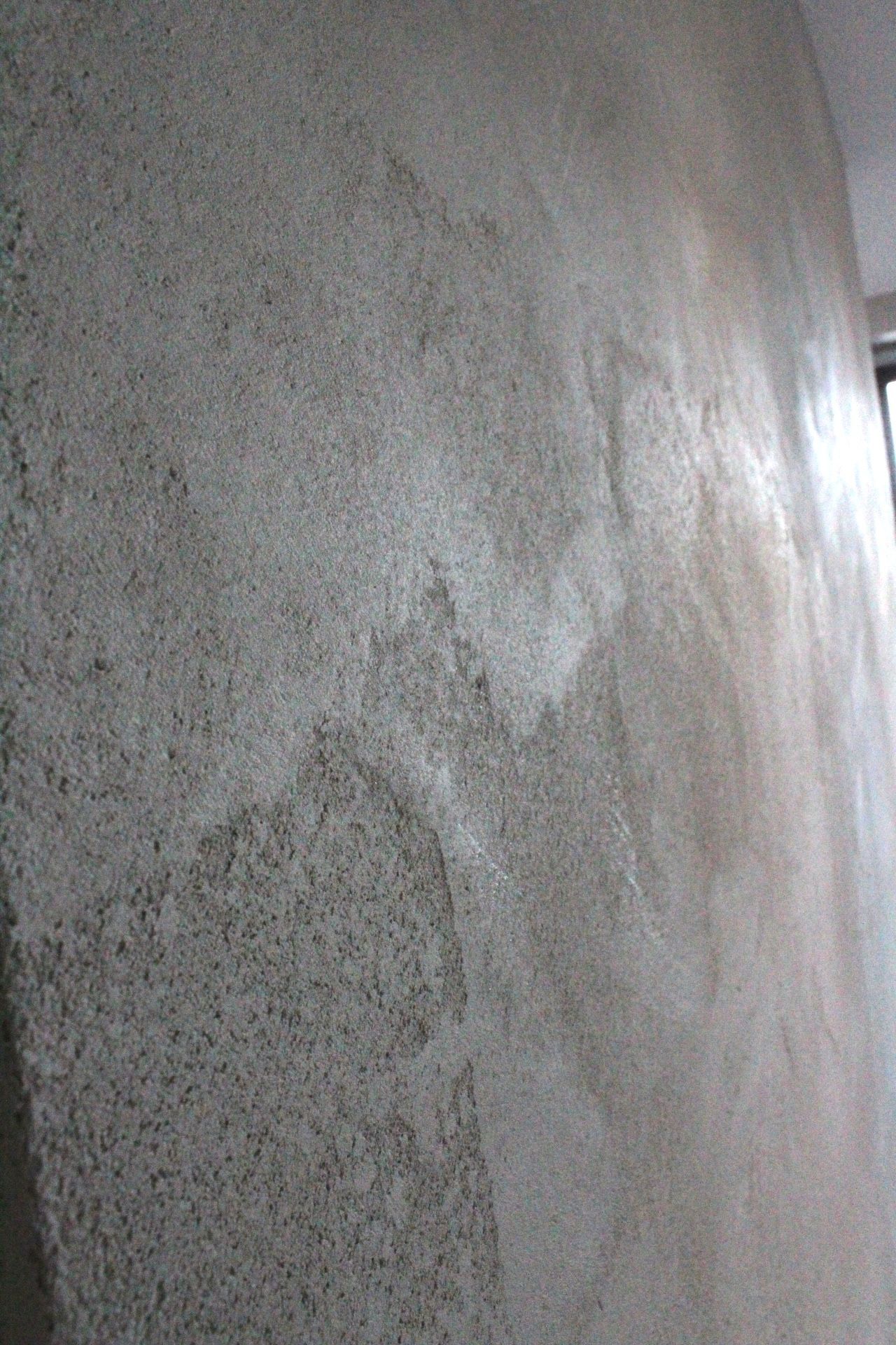 Mur gris texturé avec des stries plus claires et un coin visible.