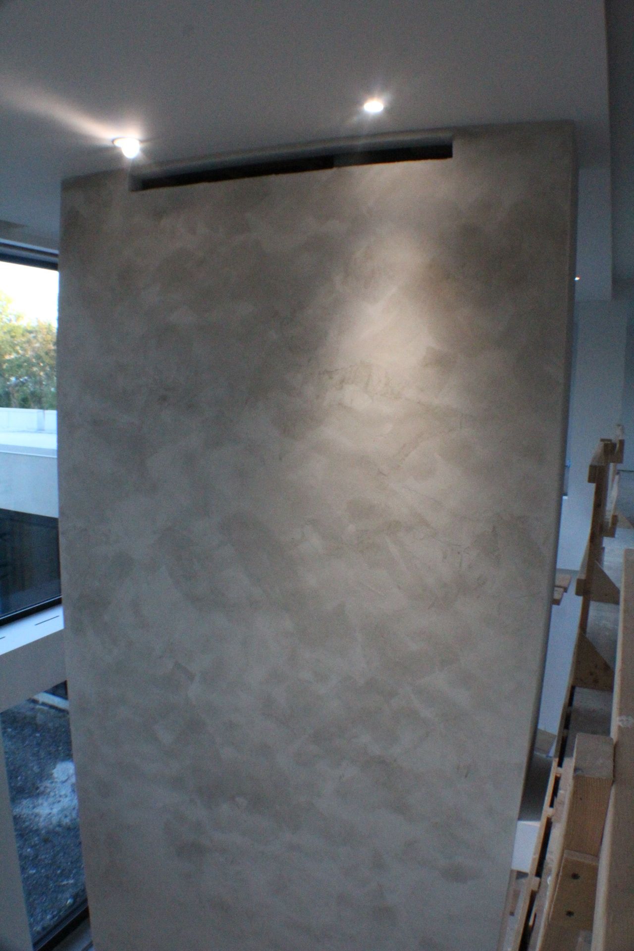 Mur gris haut et texturé avec éclairage encastré et ventilation ; aménagement intérieur.