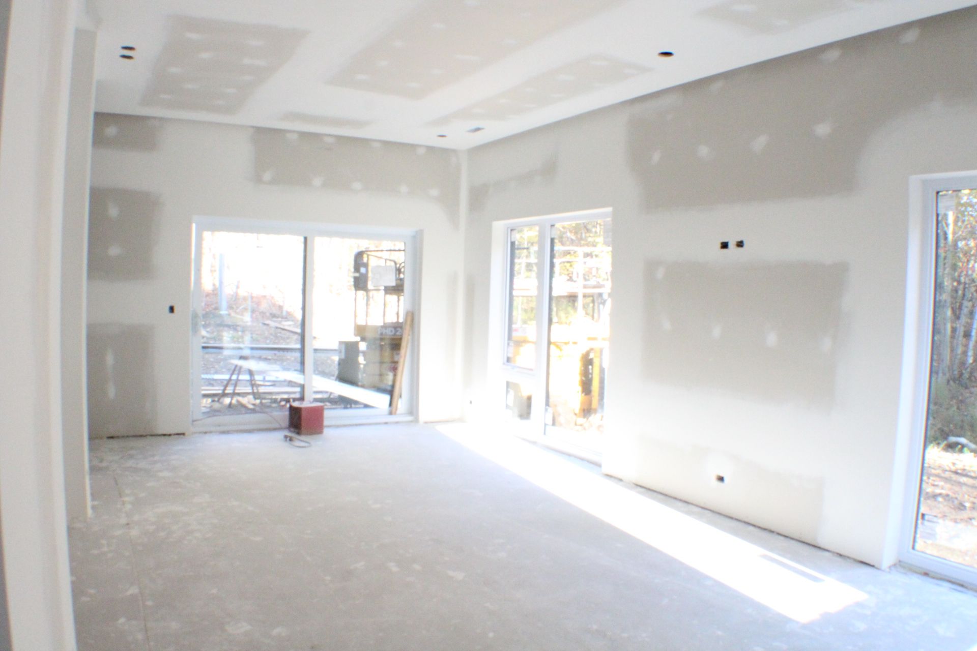 Intérieur d'une pièce en construction; cloisons sèches installées, fenêtres présentes.