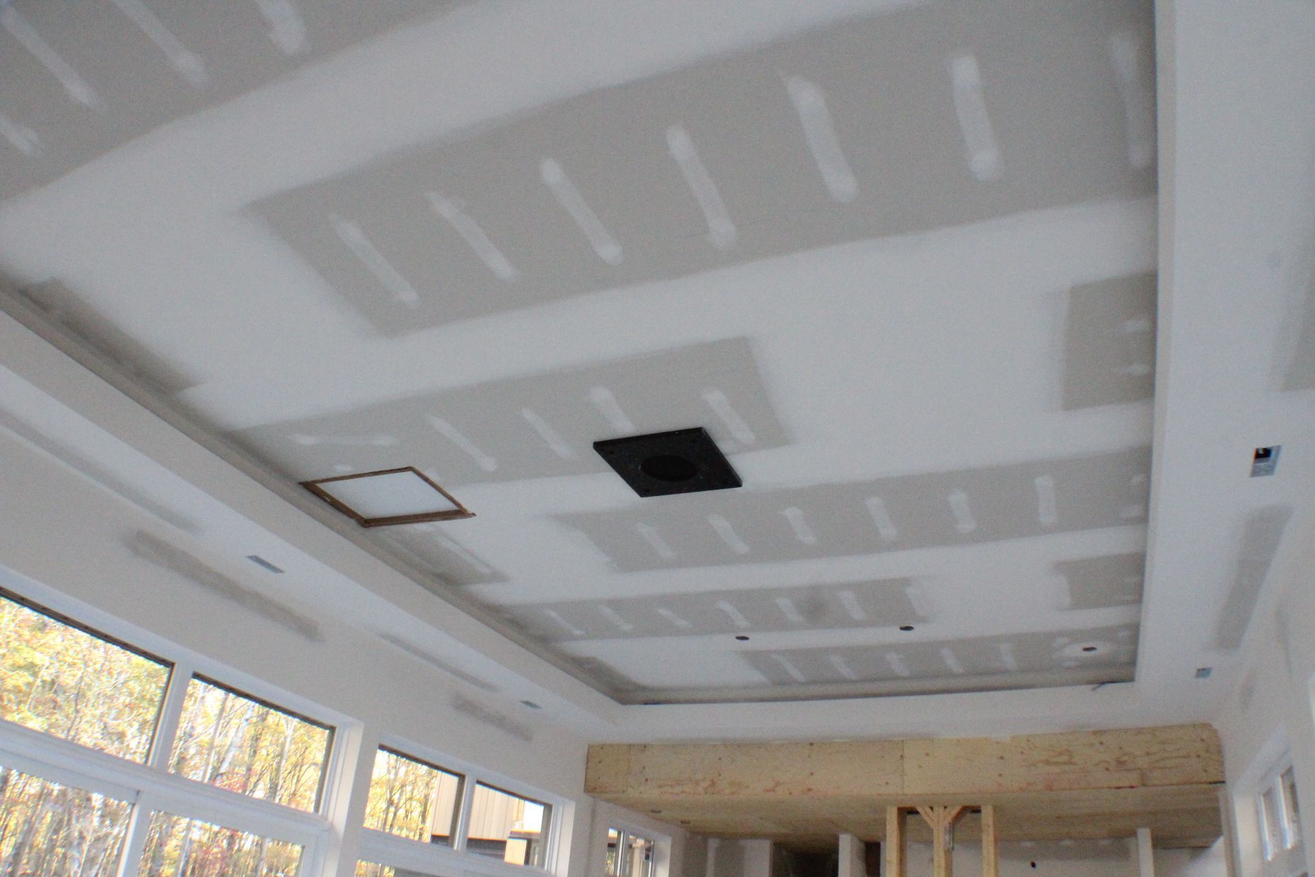 Plafond avec installation de cloisons sèches, comprenant des zones encastrées, une bouche d'aération et un panneau d'accès.