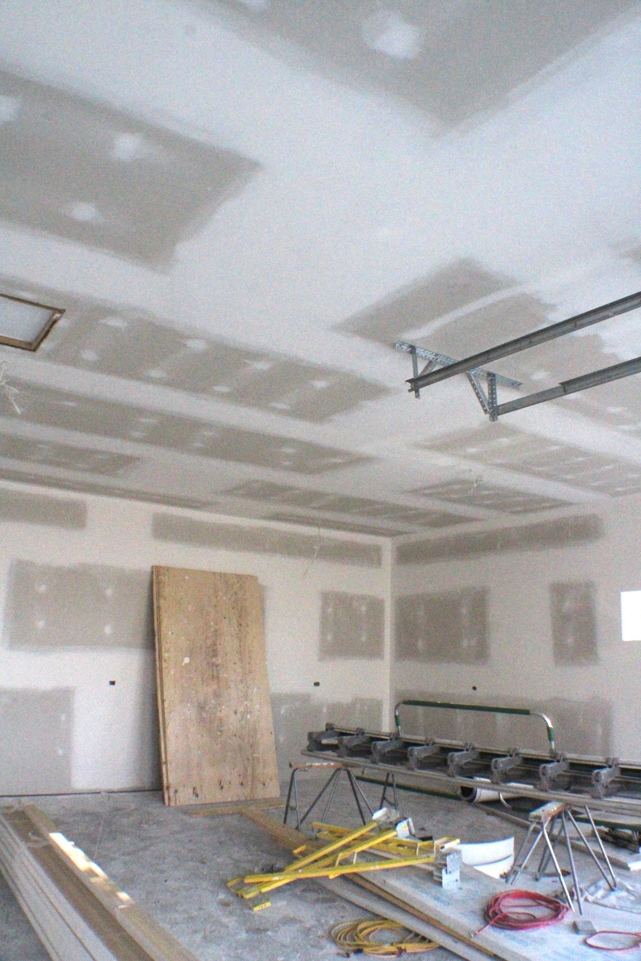 Intérieur de chantier avec cloisons sèches aux murs et au plafond. Outils et bois à disposition.