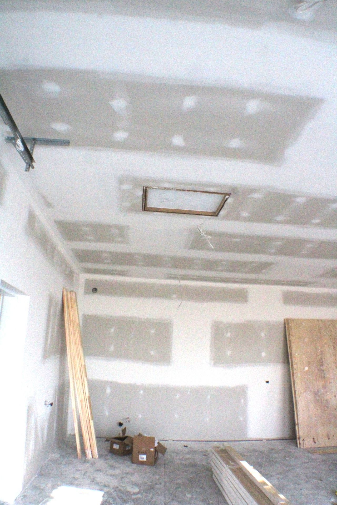 Intérieur en travaux : murs et plafond en plaques de plâtre. Planches au sol, espace non fini.