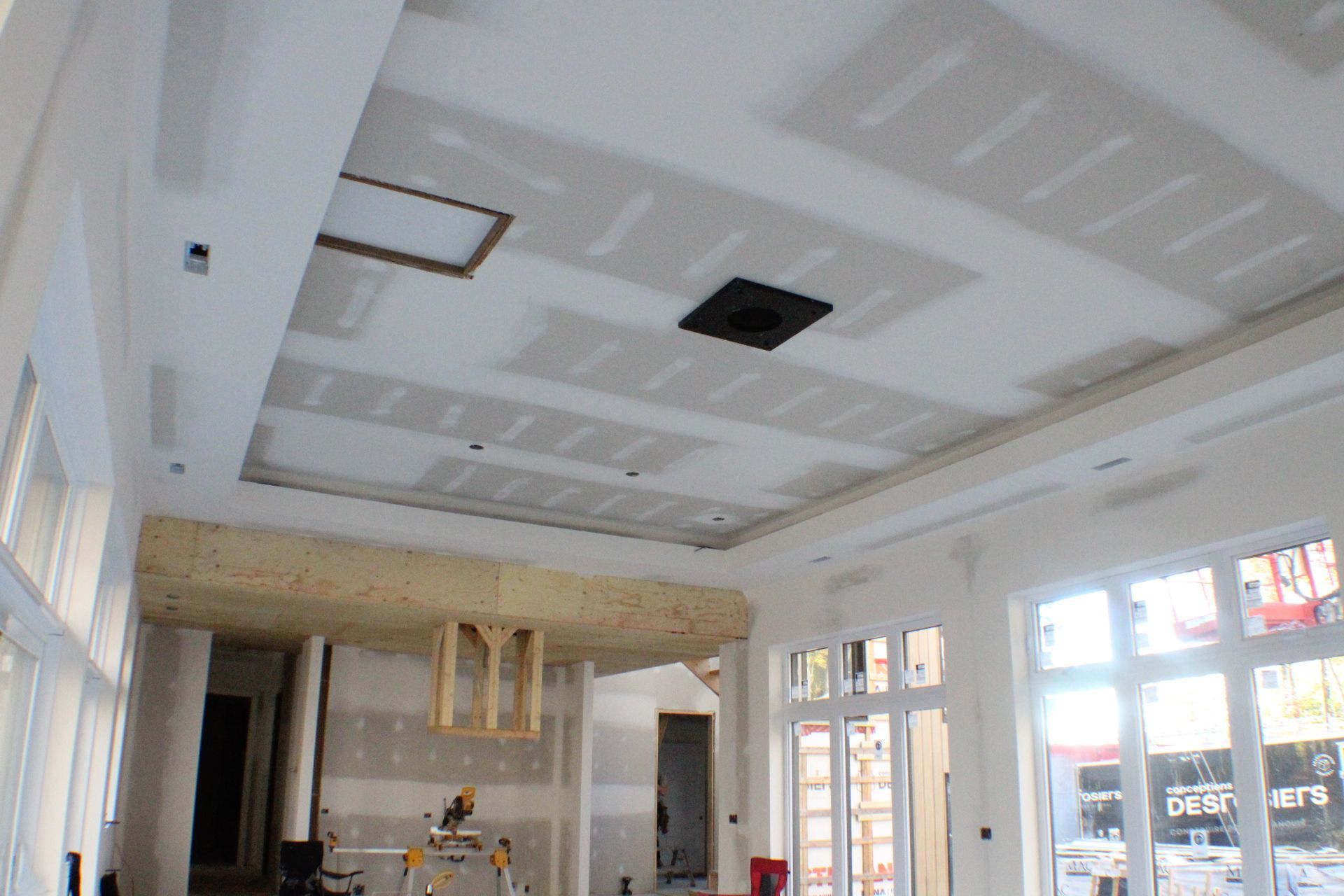 Plafond en construction; cloison sèche partiellement installée, éclairage encastré et boîte de ventilation visibles.