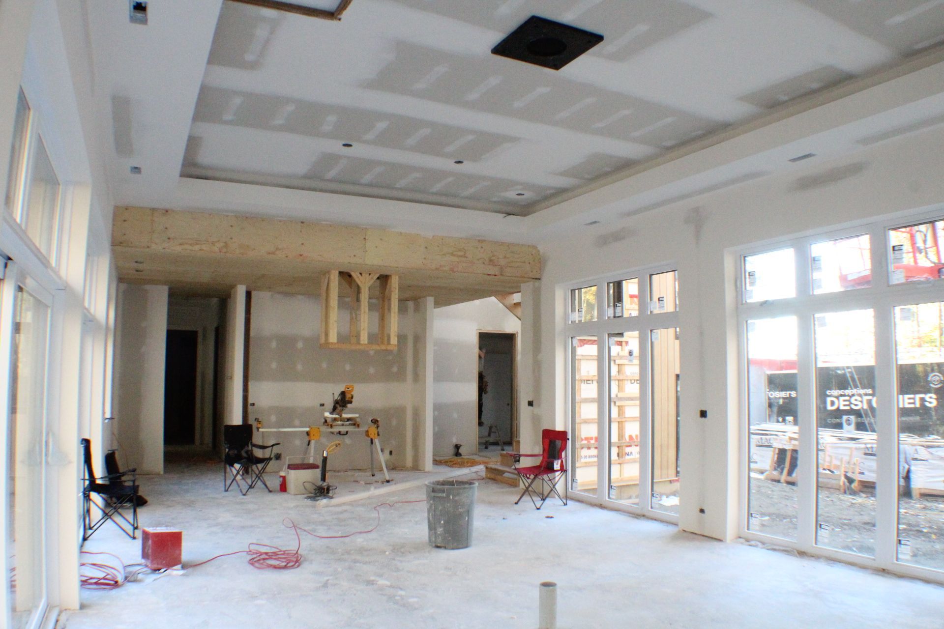 Aménagement intérieur d'une pièce avec fenêtres, cloisons sèches et outils.