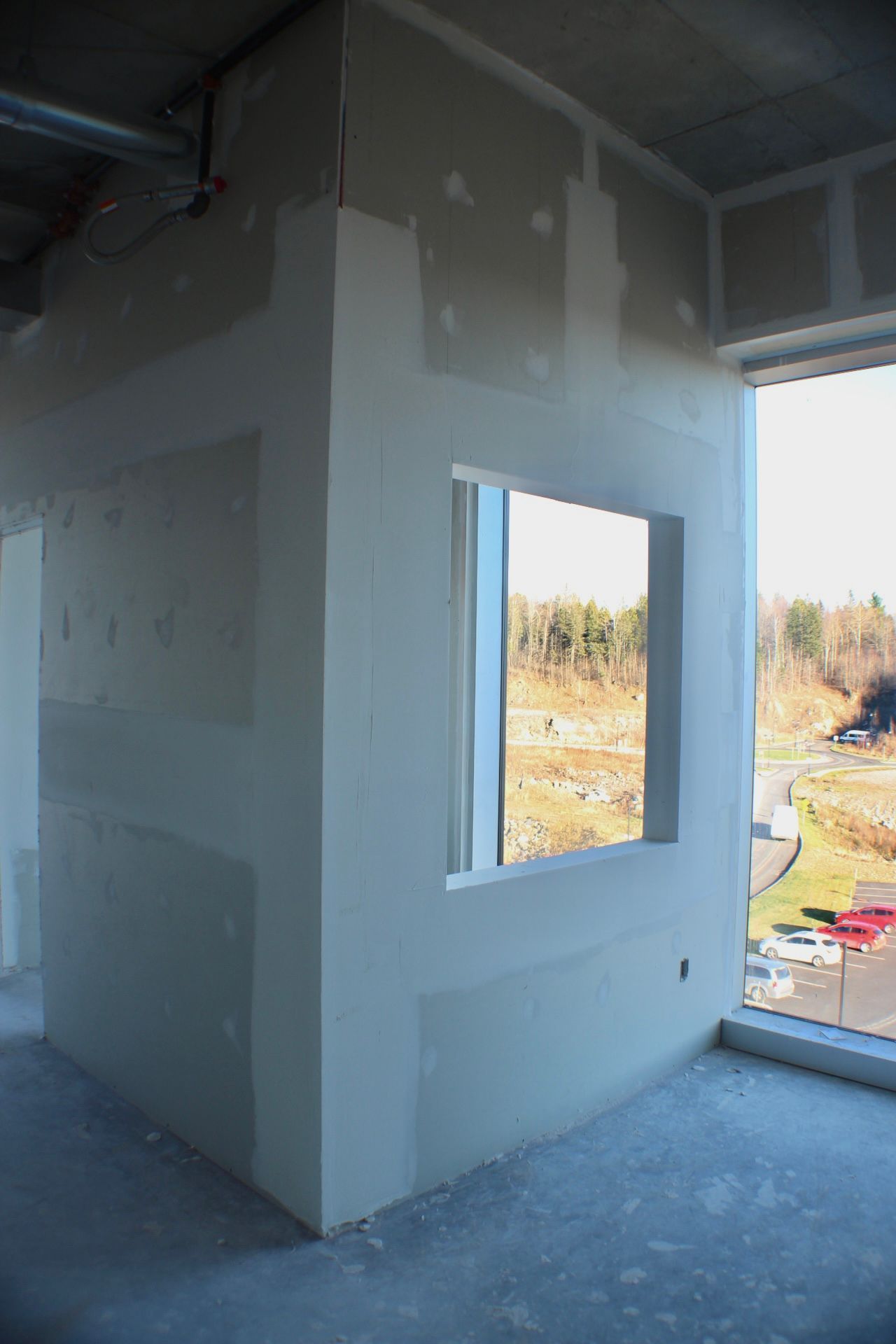 Coin intérieur avec cloison sèche autour d'une fenêtre, construction inachevée.