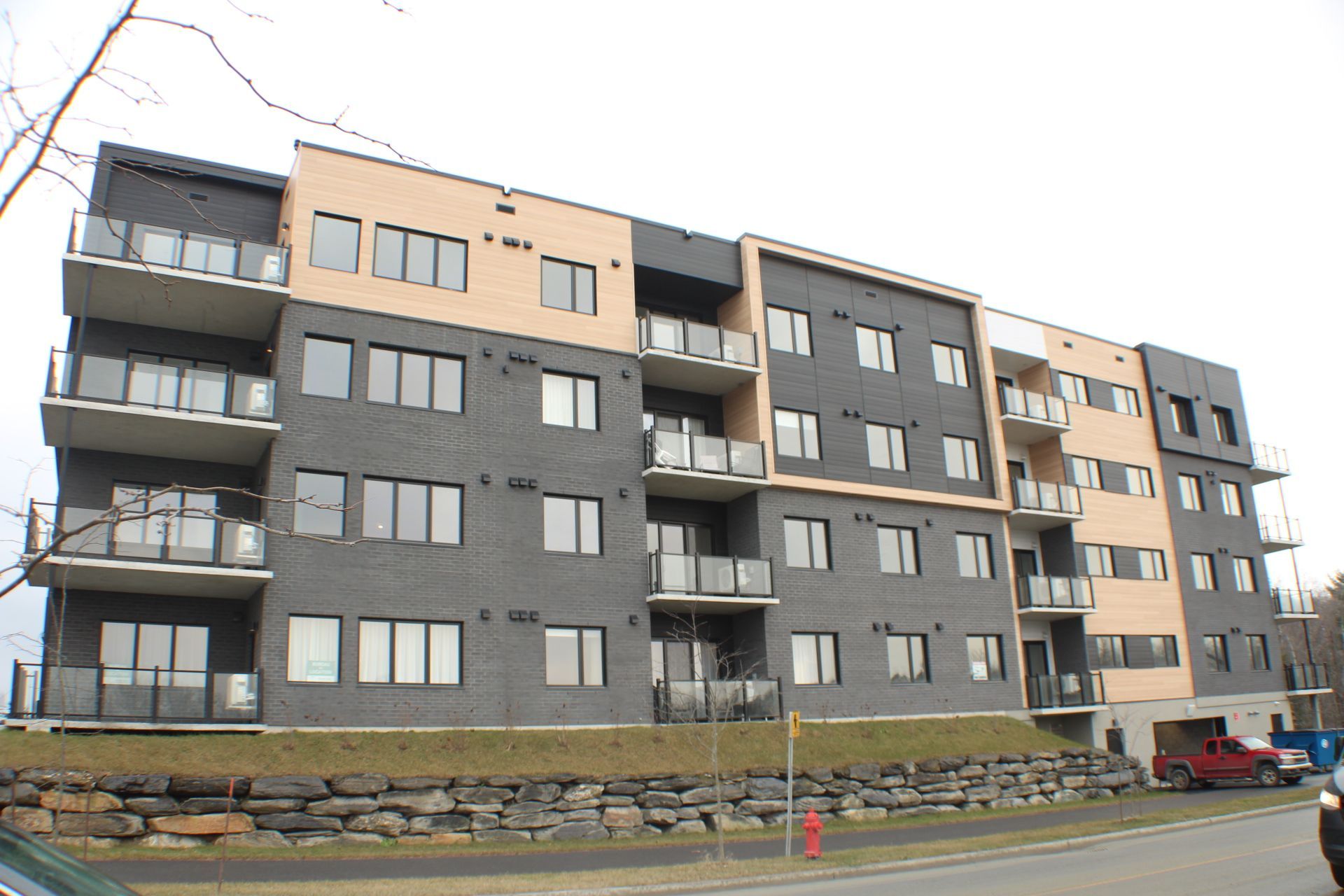 Immeuble d'appartements moderne à plusieurs étages avec balcons et différentes nuances de murs extérieurs gris et beige.