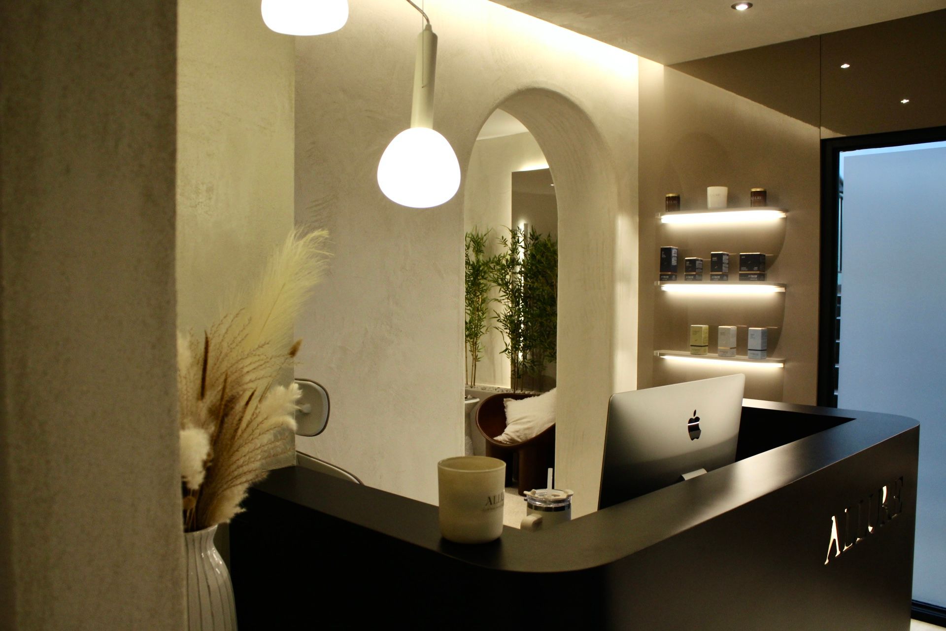 Réception d'un spa avec arche incurvée et éclairage tamisé. Herbe de la pampa et produits exposés.
