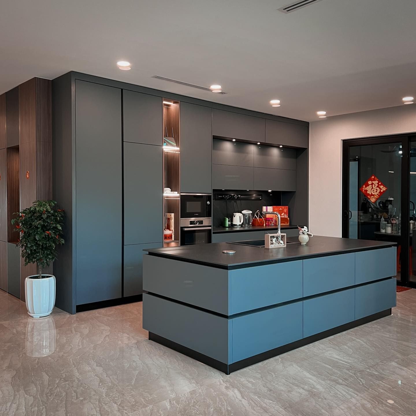 There is a large island in the middle of the kitchen.Fenix grey dry kitchen