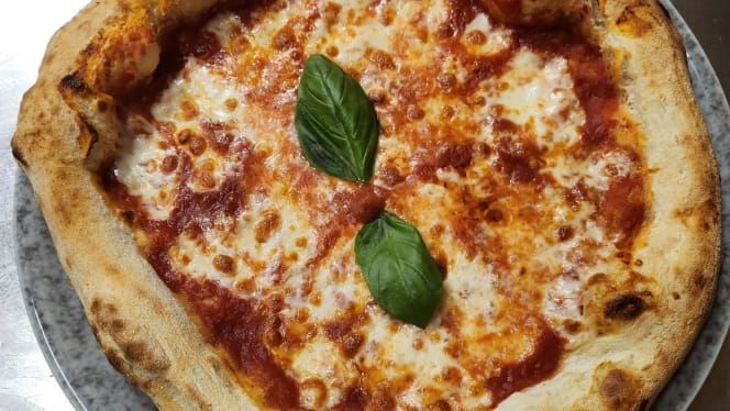 Pizza Margherita con salsa di pomodoro, mozzarella e basilico su un piatto grigio.