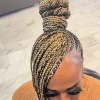 Woman with blonde and brown braided hair in a bun, looking down.