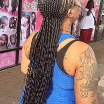 Woman with long braided hair and a blue tank top, showing off a large tattoo.
