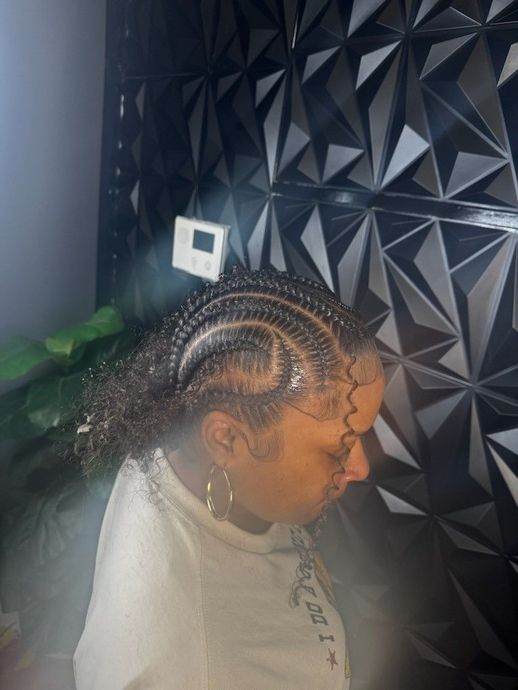 Blonde woman with wavy hair getting styled in a salon; hands are adjusting her hair, near a window.