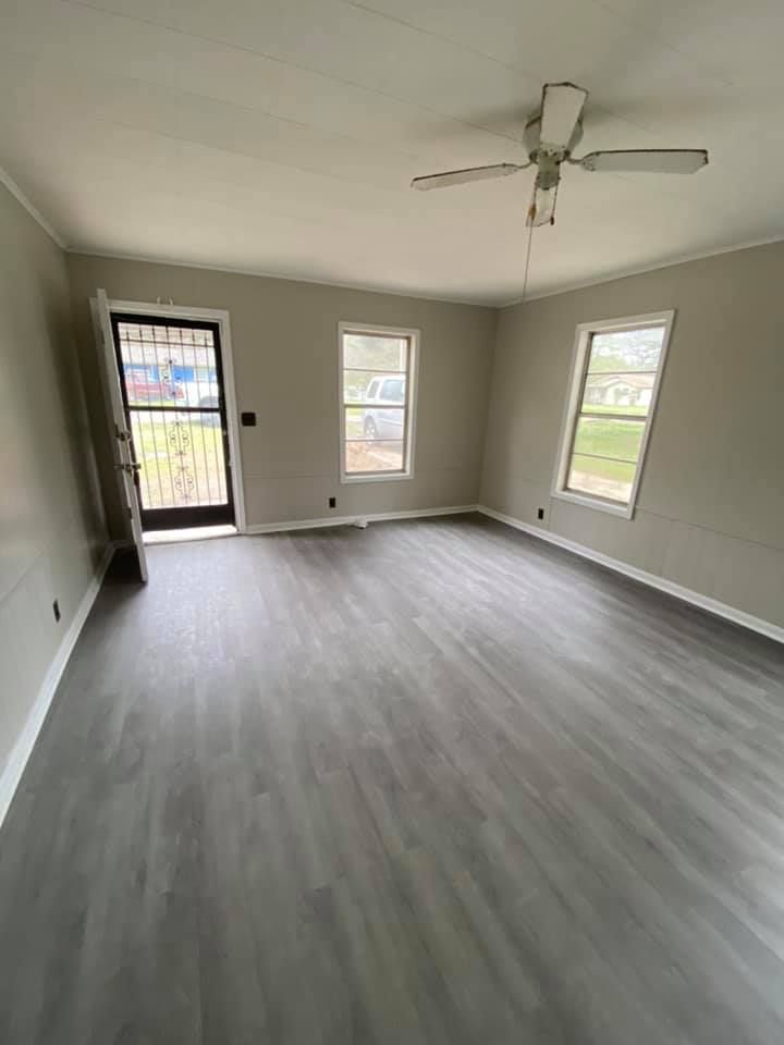 An empty living room with hardwood floors and a ceiling fan.