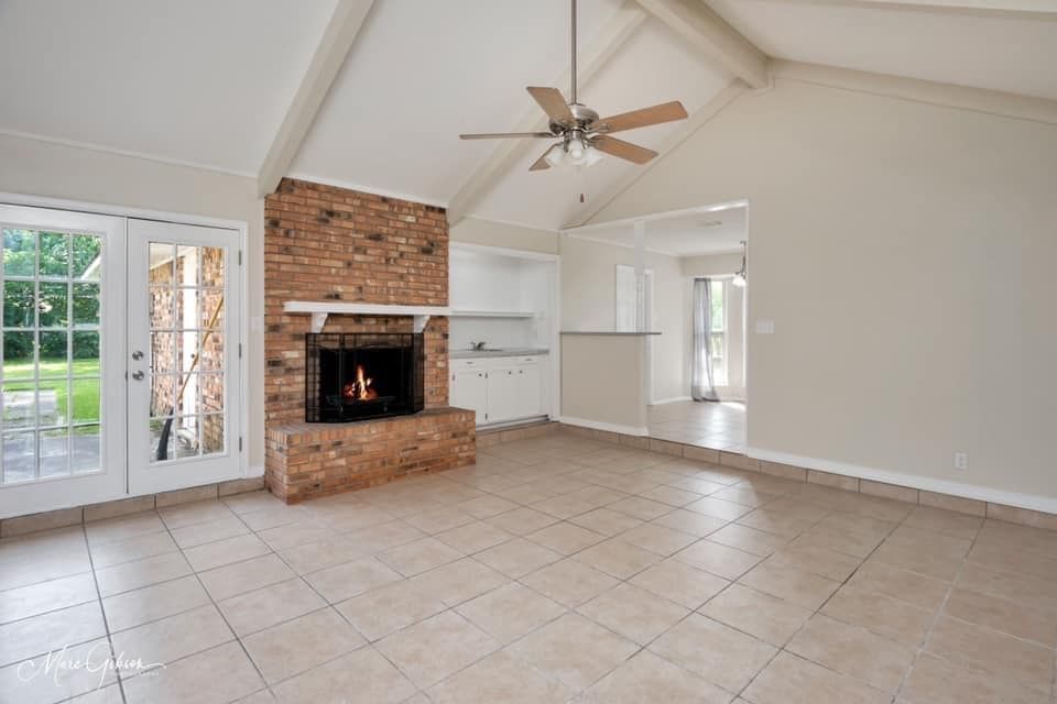 An empty living room with a fireplace and a ceiling fan.