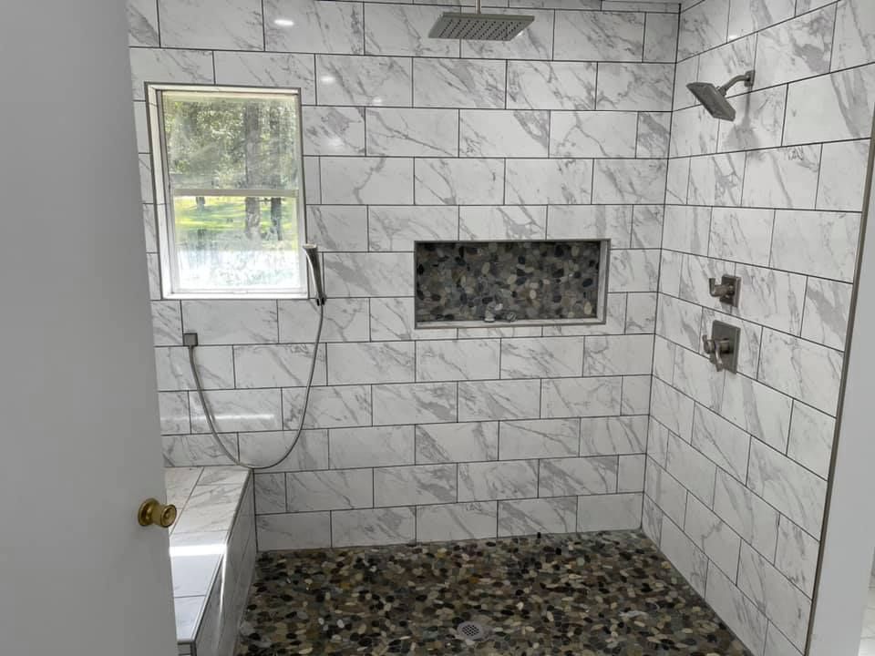 A bathroom with a walk in shower and a window.